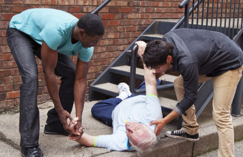 two people helping up a elderly person from the ground