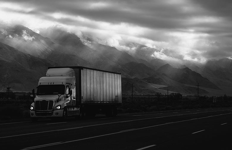 black and white image of a truck driving down the highway